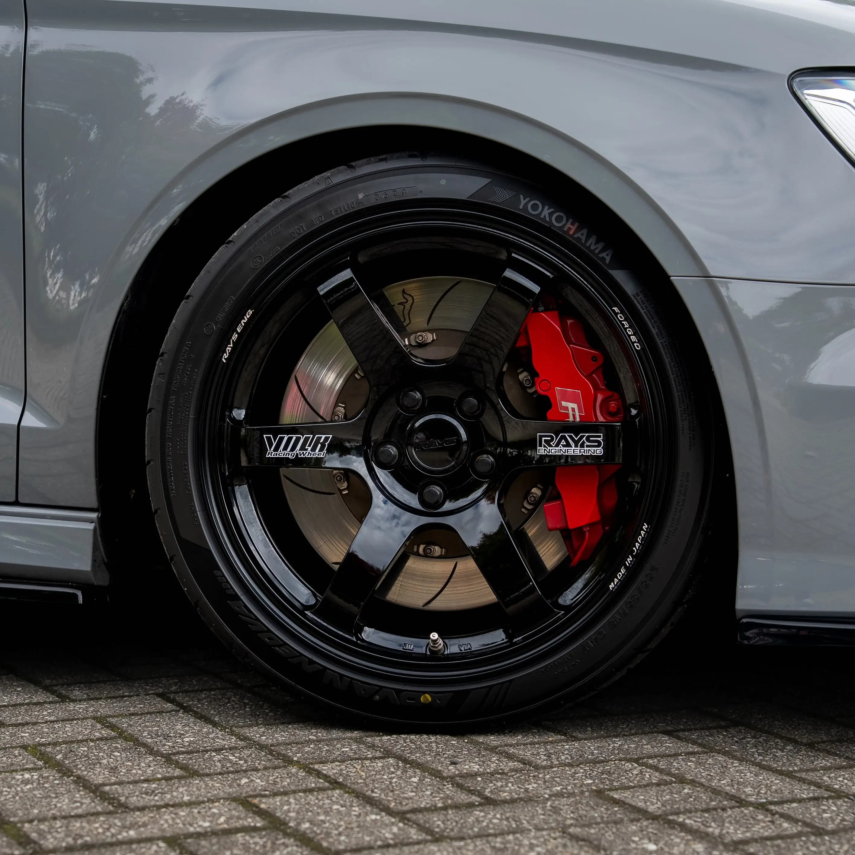 close up details of Nardo Grey Audi RS3 8V sedan fitted with gloss black RAYS Volk Racing TE37 Saga SL wheels in 18x9.5 +45 spec with black sticker