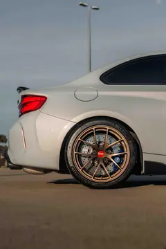 Rear three quarter perspective of a BMW F87 M2 highlighting the deep barrel profile of Matte Bronze BBS RI-A track wheels