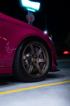 Front three-quarter angle of Ruby Star Pink Audi RS3 8V Sedan running Matte Gun Bronze RAYS TE37 SAGA SL forged wheels