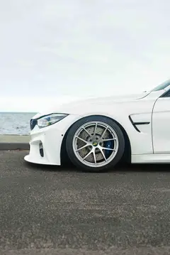 Low angle dynamic shot of a lowered white BMW M3 equipped with motorsport spec BBS RIA wheels