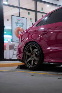 Rear profile of Ruby Star Pink Audi 8V RS3 Sedan with 5x112 Matte Gun Bronze RAYS Volk Racing TE37 SAGA SL wheels from KA Autosport