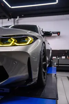 Stance shot of a modified BMW G80 M3 sedan riding on staggered gloss black RAYS TE37 wheels