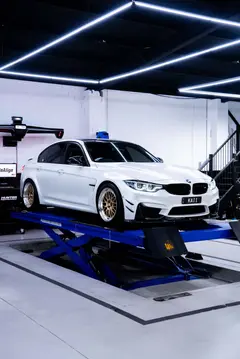 Front three-quarter view of a white BMW F80 M3 running forged mesh-style Volk Racing 21A wheels in Gold