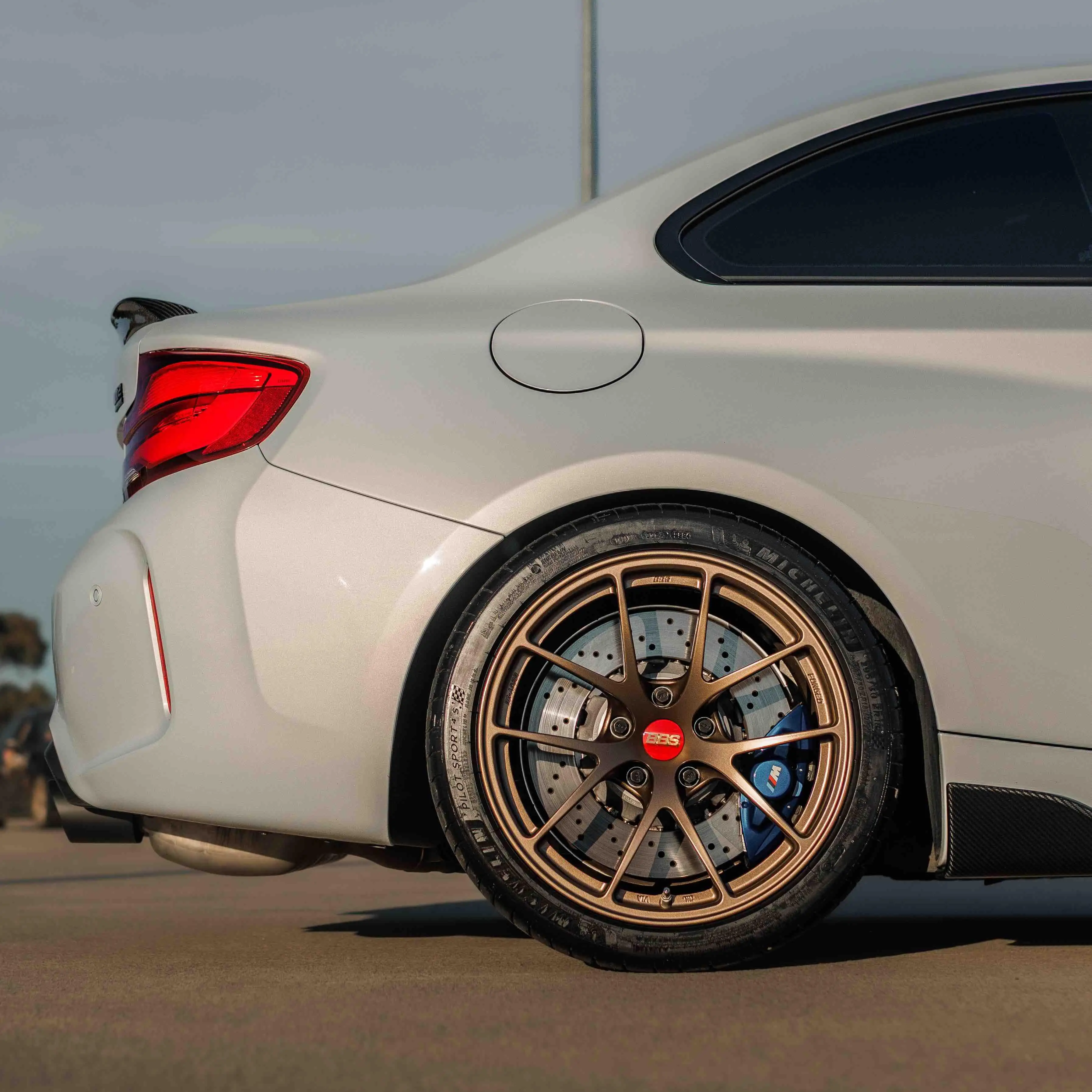 Rear three quarter perspective of a BMW F87 M2 highlighting the deep barrel profile of Matte Bronze BBS RI-A track wheels