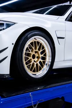 Close up of blue M Performance brake calipers showing through the gold spokes of a Volk Racing 21A wheel