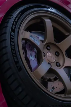Close-up of Matte Gun Bronze RAYS TE37 SAGA SL wheel and RS big brake clearance on Ruby Star Pink Audi 8V RS3